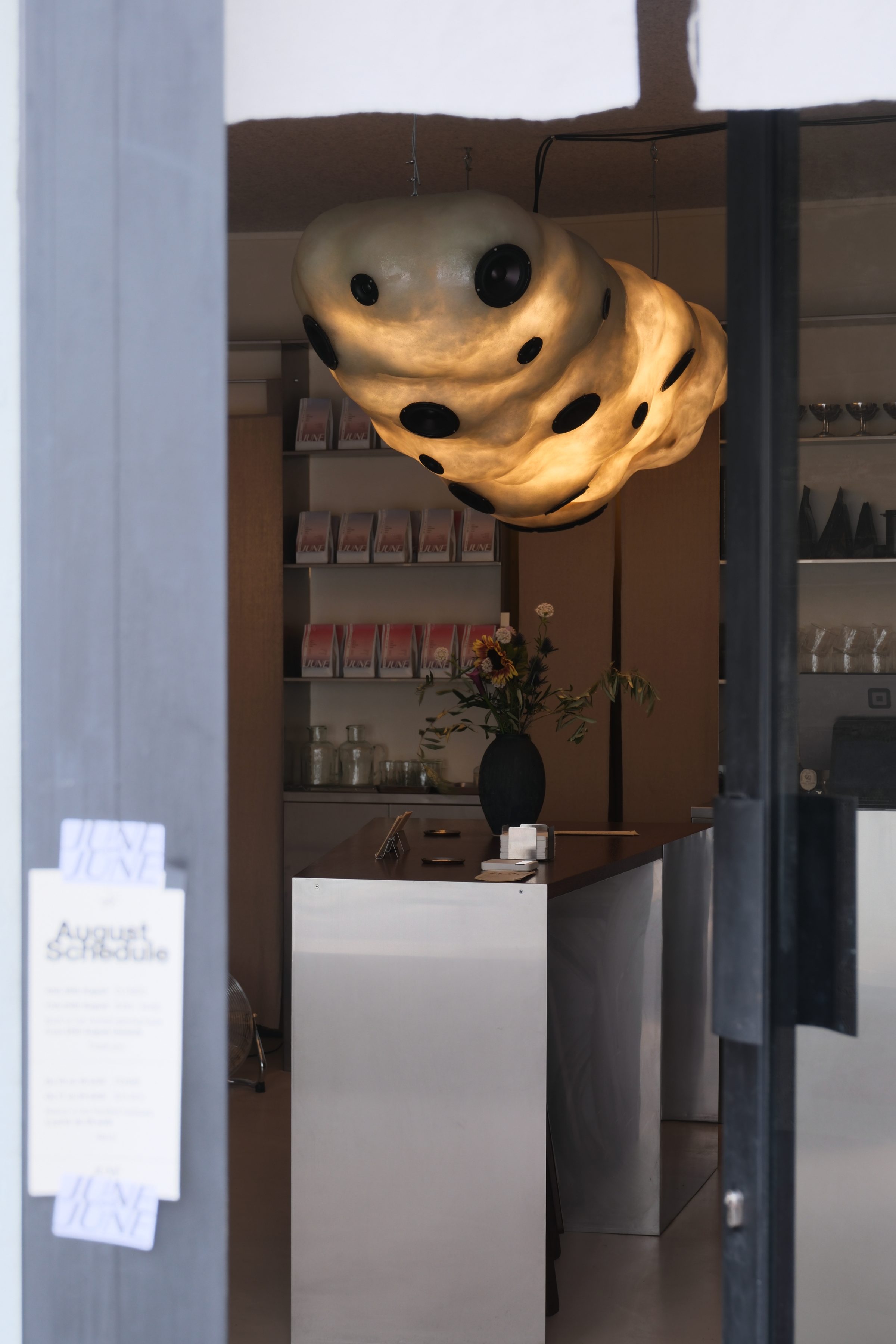 The counter at 13B Rue Pradier — bags on the shelf under the cloud lamp